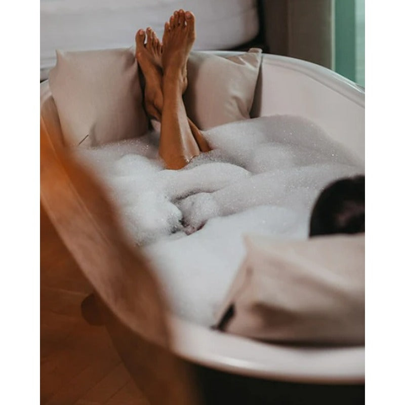 Entspannte Füße auf dem Badesofa Fußkissen in einer mit Schaum gefüllten Badewanne