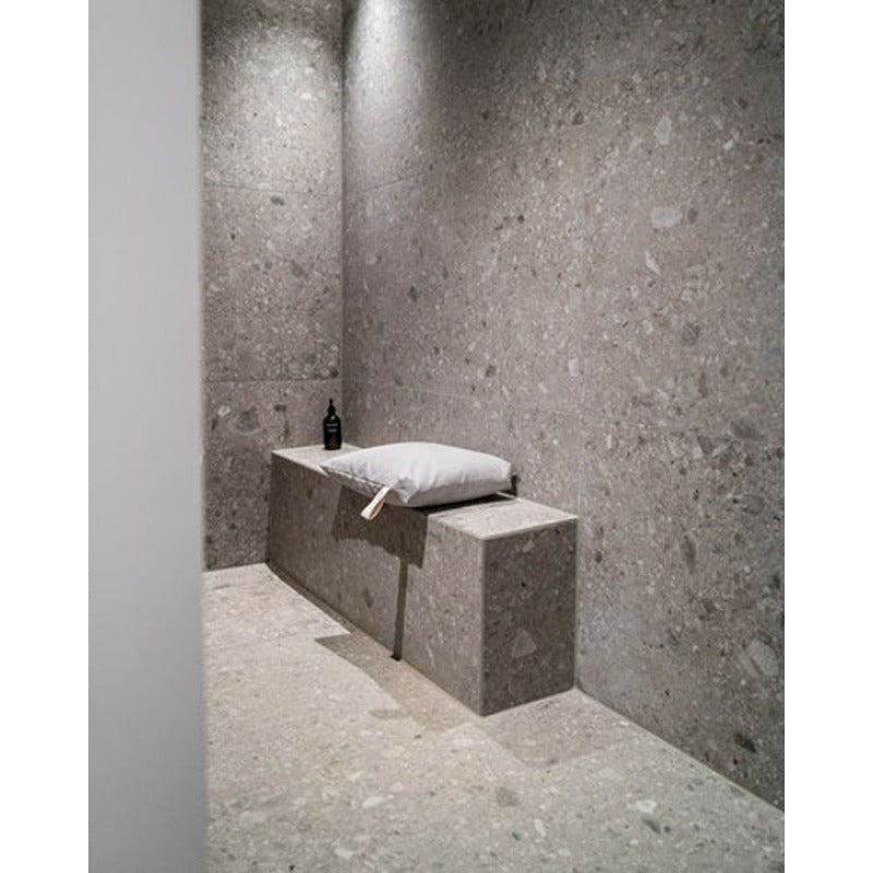 Hellgraues Badesofa Sitzkissen auf moderner Duschbank in grauer Natursteinumgebung